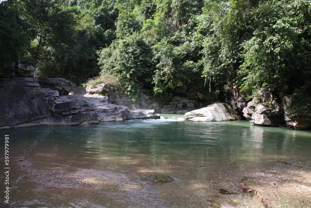 Tropical landscape. Mountain river in a tropical rainforest. A small pond with stone banks among the jungle. Tropical landscape. Mountain river in a tropical rainforest. A small pond with stone banks among the jungle.