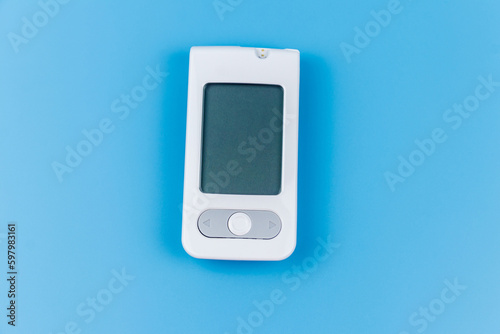 Digital glucometer on a pastel blue background. Diabetes concept