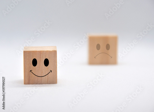 Happy and sad emotion faces on wooden cubes with white background cover. Customer feedback, satisfaction and evaluation concept