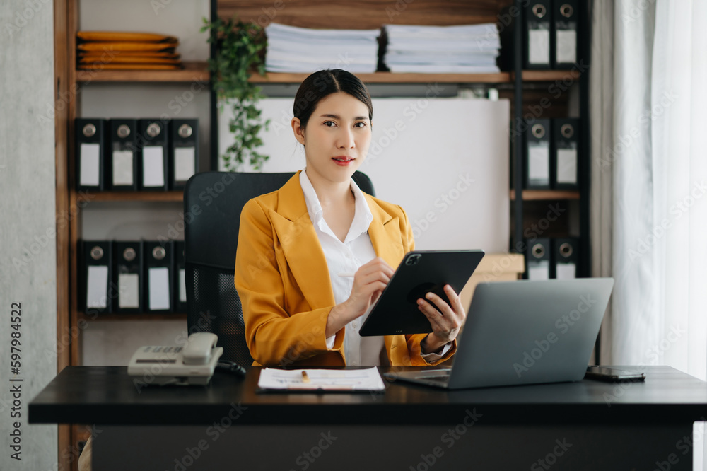 Business woman using tablet and laptop for doing math finance on an office desk, tax, report, accounting, statistics, and analytical research concept in office.