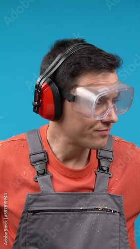 Upset male carpenter in goggles and earmuffs