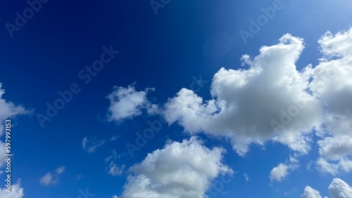 Ideal summer day with clear blue sky and soft white clouds. Creates peaceful feelings, perfect for ads and websites that convey a relaxed mood.