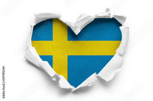 Heart shaped hole torn through paper, showing satin texture of flag of Sweden, cut out