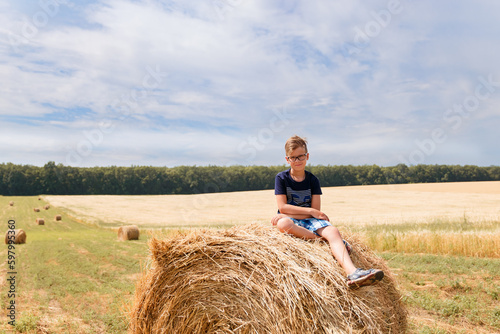 Children on round bales, mowed wheat, bales of wheat, children in Ukraine, wheat field, children in a wheat field with a beautiful sky, bales 