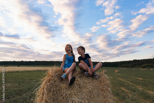 Children on round bales, mowed wheat, bales of wheat, children in Ukraine, wheat field, children in a wheat field with a beautiful sky, bales