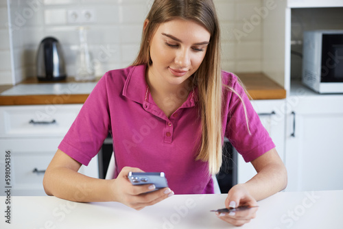 Customer paying online with a credit card. Young blonde woman making a purchase online with a smart phone app