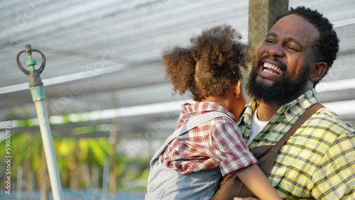 African American father and daughter playing with each other inside the vegetable garden.
