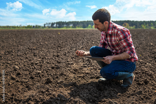 Male farmer in the field checks the soil. Selective focus.