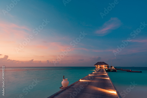 Amazing sunset landscape. Picturesque summer sunset in Maldives. Luxury resort villas seascape with soft led lights under colorful sky. Dream sunset over tropical sea, fantastic nature dream