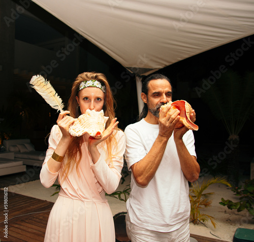 beautiful girl and mexican chaman using a shell to produce chamanic sounds photo