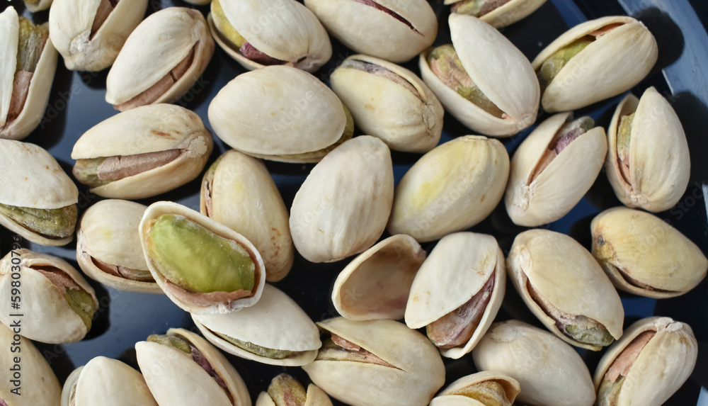 A closeup view of a Single Pistachio seed open in a pile of pistachio A closeup view of a Single Pistachio seed open in a pile of pistachio