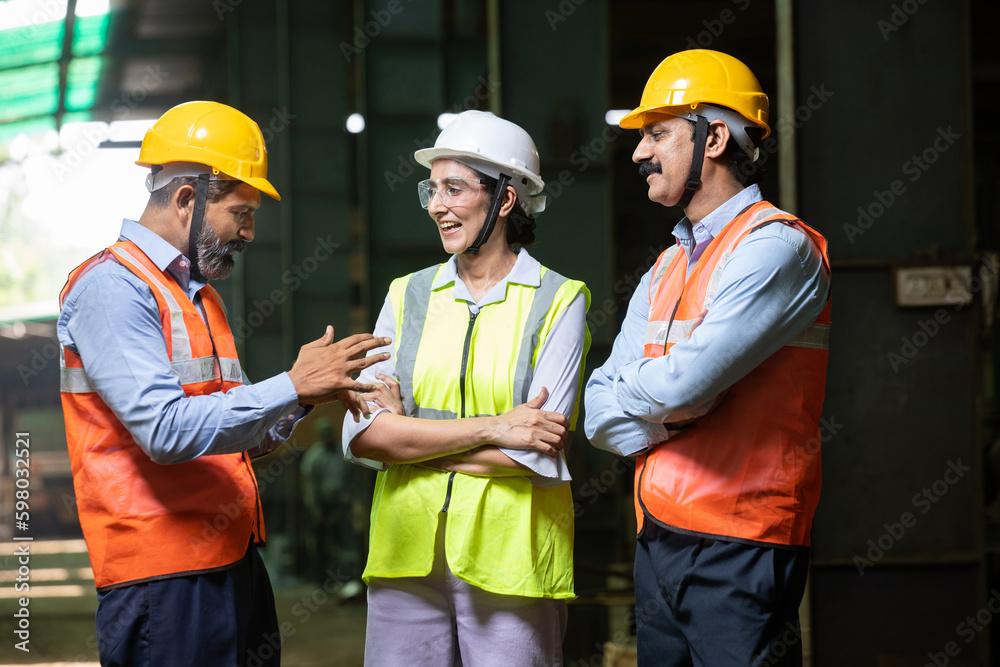 Group of Indian engineers wearing helmet and vest discussing and laughing, candid moment, Industrial factory concept, male and female worker smiling chatting in free time at project. work culture. Group of Indian engineers wearing helmet and vest discussing and laughing, candid moment, Industrial factory concept, male and female worker smiling chatting in free time at project. work culture.