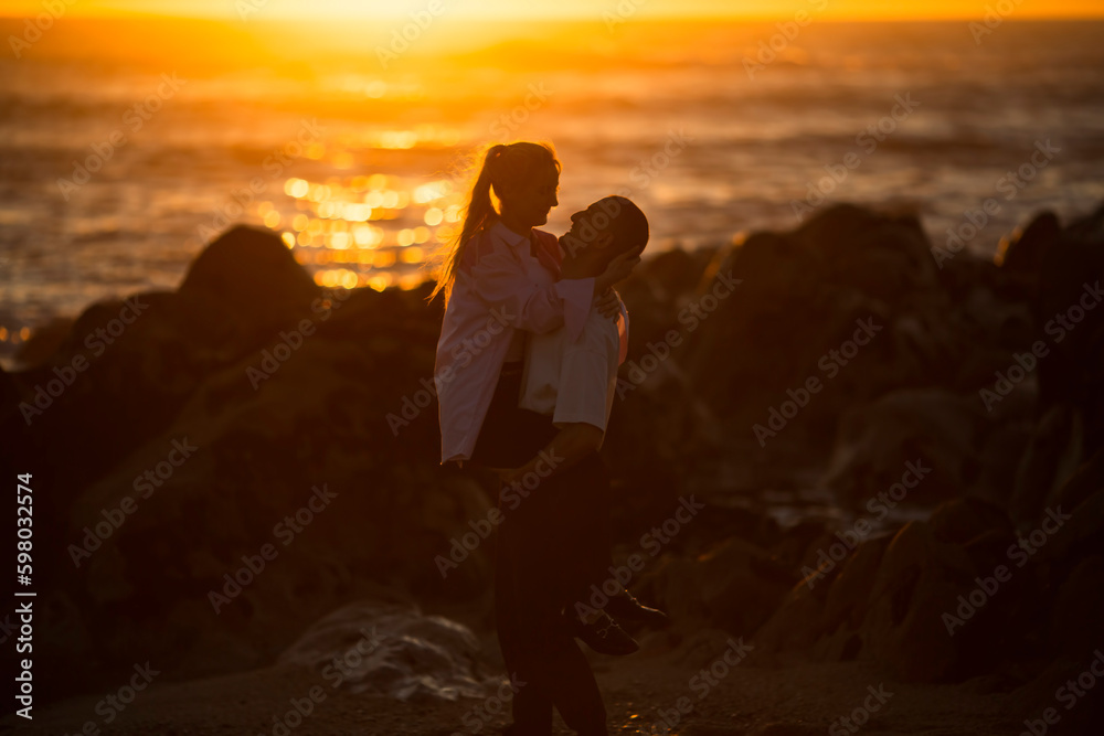 Fototapeta premium A young couple in love having fun on the ocean during a golden sunset. .