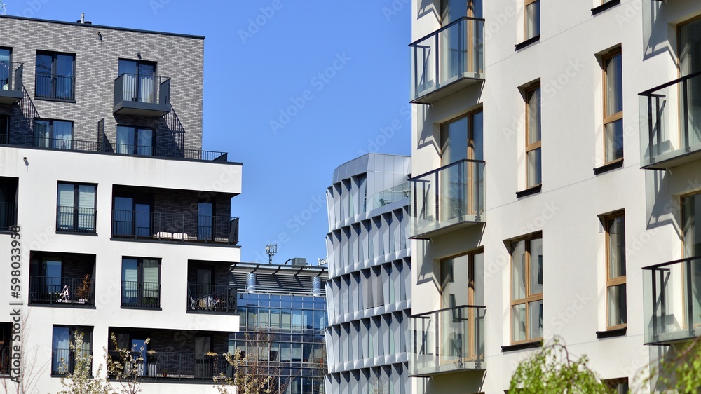 Obraz premium Modern apartment buildings on a sunny day with a blue sky. Facade of a modern apartment building. Contemporary residential building exterior in the daylight. 