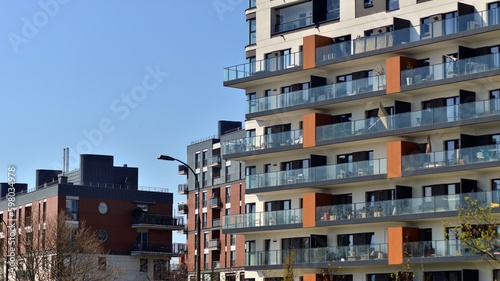 Modern apartment buildings on a sunny day with a blue sky. Facade of a modern apartment building. Contemporary residential building exterior in the daylight.  © Grand Warszawski