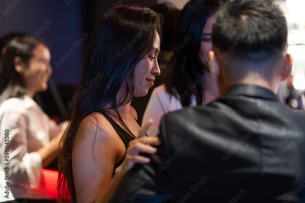 Diverse group of friends partying in nightclub and toasting drinks. Asian female drink intoxicating drink