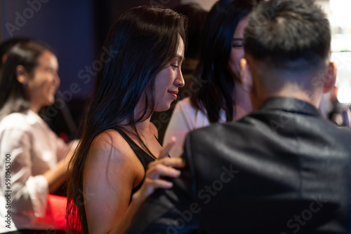 Diverse group of friends partying in nightclub and toasting drinks. Asian female drink intoxicating drink