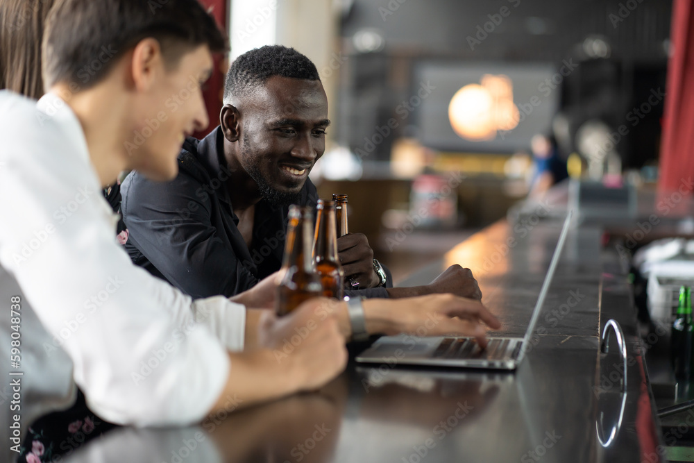 handsome young African American man looking at laptop computer screen. Black businessman and friends video call on laptop computer at the club. handsome young African American man looking at laptop computer screen. Black businessman and friends video call on laptop computer at the club.