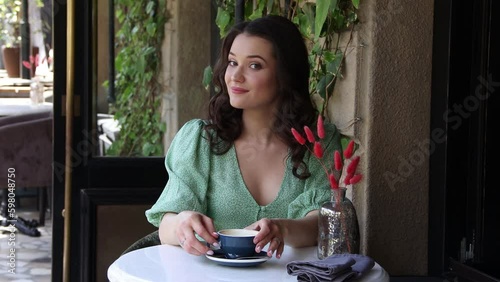 Girl drinks coffee in street cafe in summer. 4K Resolution