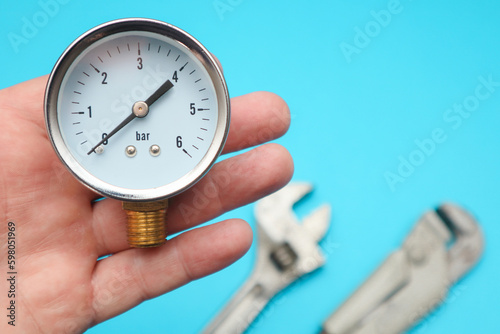 Pressure gauge in hand, measuring instrument close up on pneumatic or hydraulic control system. Plumbing concept or service water worker. Pipe.