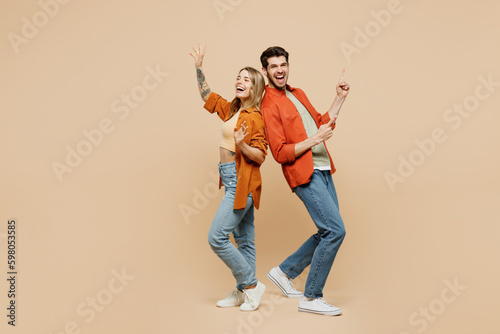 Full body fun young couple two friends family man woman wear casual clothes point index finger aside on area waving hand together isolated on pastel plain light beige color background studio portrait. © ViDi Studio