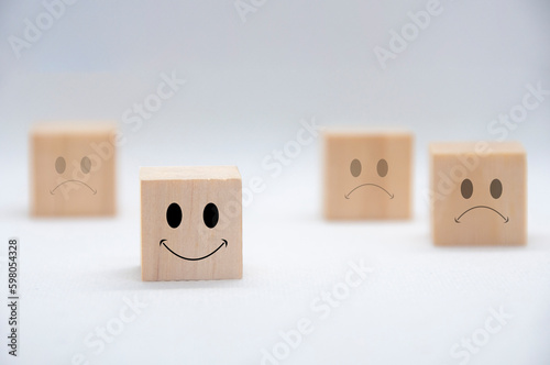 Happy and sad emotion faces on wooden cubes with white background cover. Customer satisfaction and evaluation concept.