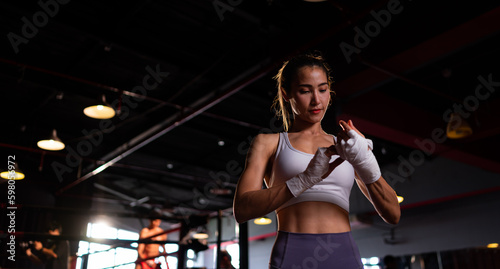 Portrait of woman learning Muay Thai to build up the strength of the body and use it for self-defense. Are using hand wraps before putting on boxing gloves for boxing