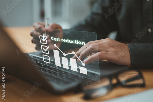 Businessman lowering the arrow of a graph, concept of cost reduction. Along with the down arrow, emphasizes the importance of effective budgeting and cost management strategies in business.