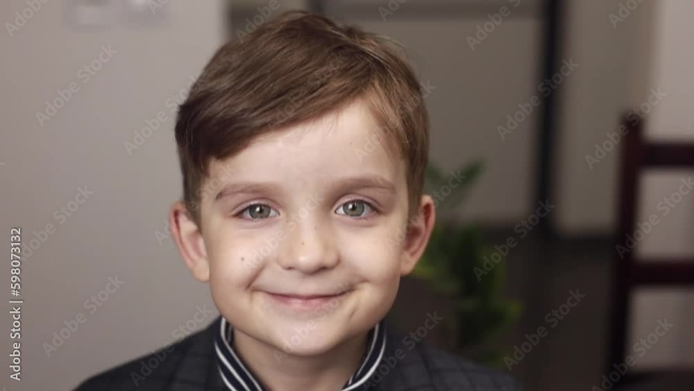 Close-up portrait of a cute boy 7 years old, who looks into the frame with big green eyes and smiles Close-up portrait of a cute boy 7 years old, who looks into the frame with big green eyes and smiles