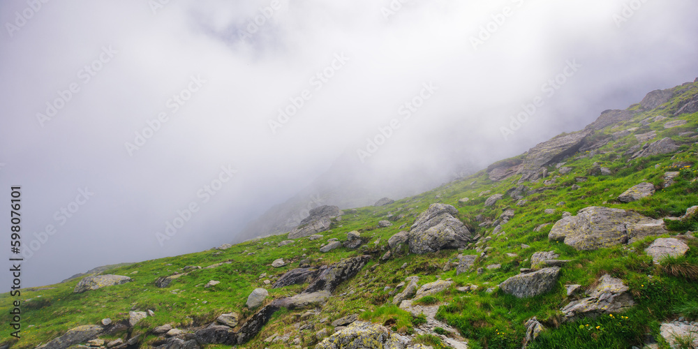 steep slopes of fagaras mountains, romania. rocks and boulders among the grass. foggy weather. mysterious adventures