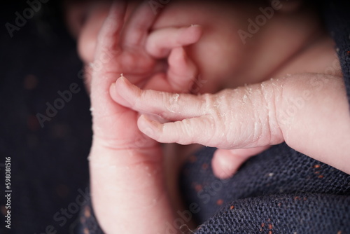 A tiny cute baby born one week old. Newborn peeling. Newborn Baby's hands and face skin with skin peels. close up of hands new baby born details.