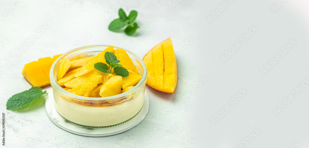 greek yogurt and mango in glass jars on a light background. Restaurant menu, dieting, cookbook recipe Long banner format. top view greek yogurt and mango in glass jars on a light background. Restaurant menu, dieting, cookbook recipe Long banner format. top view