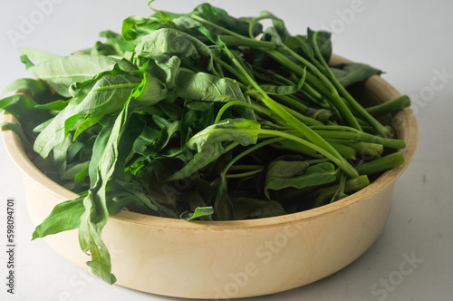 Water spinach leaves that have been selected and picked from the stems are placed in a plastic container isolated on a white background