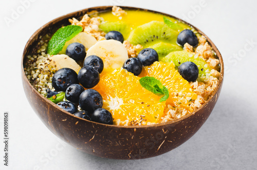 Smoothie Bowl with Orange, Kiwi, Banana, Blueberry, and Granola in a Coconut Bowl, Healthy Food Concept