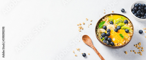 Smoothie Bowl with Orange, Kiwi, Banana, Blueberry, and Granola in a Coconut Bowl, Healthy Food Concept