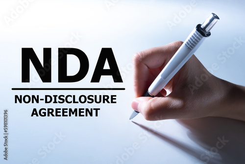 Non-disclosure agreement. Hand signs document. NDA contract. Non-disclosure agreement contract prohibiting dissemination of information. NDA for corporate employees. NDA procedure. photo