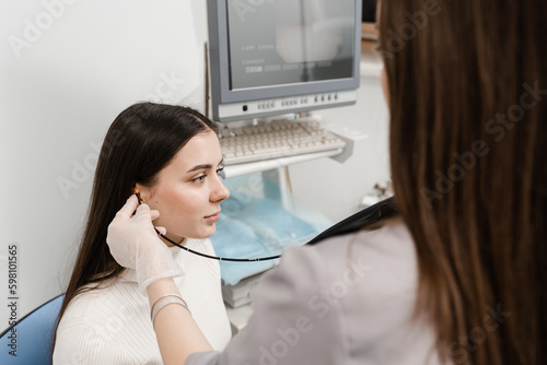 ENT doctor using fibrolaryngoscope to examine and treat the ears. ENT specialist diagnoses and treats larynx and pharynx, such as hoarseness, vocal cord nodules, tumors, infections, and inflammation. photo