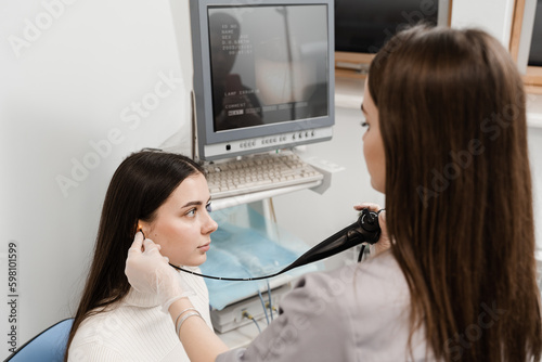 ENT doctor using fibrolaryngoscope to examine and treat the ears. ENT specialist diagnoses and treats larynx and pharynx, such as hoarseness, vocal cord nodules, tumors, infections, and inflammation. photo