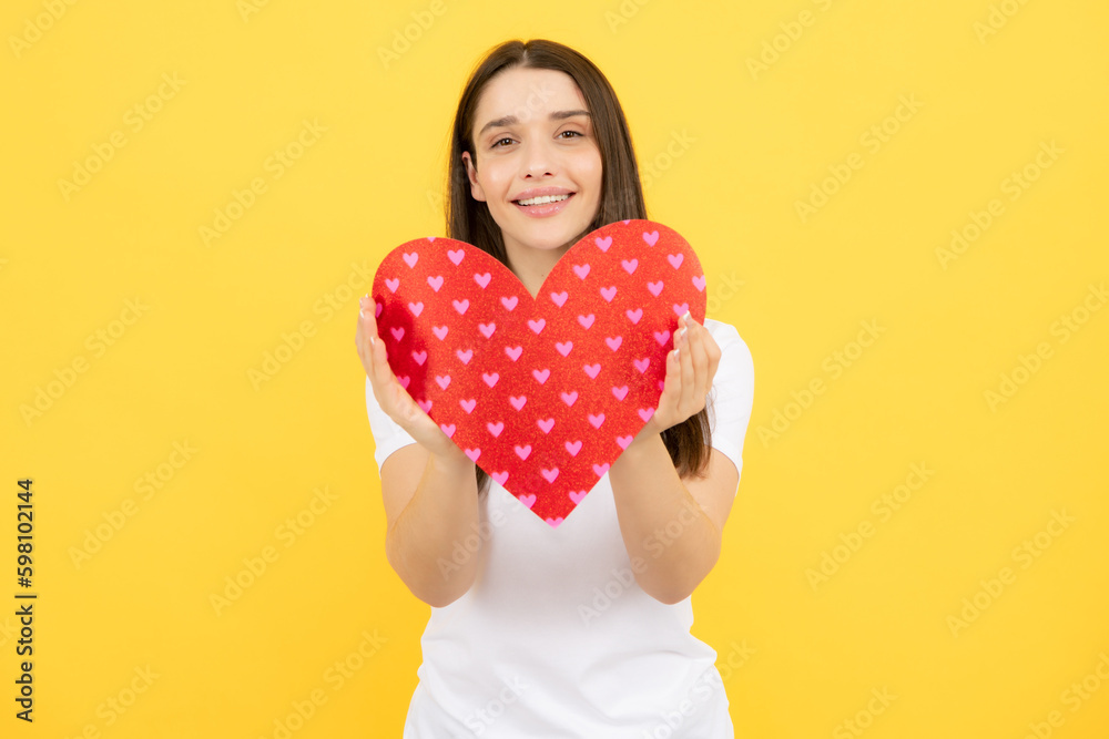 Happy woman hold red heart. Beautiful female model posing on isolated yellow background. Cheerful positive cute pretty tender girl with heart. Valentine day love and beautiful. Happy woman hold red heart. Beautiful female model posing on isolated yellow background. Cheerful positive cute pretty tender girl with heart. Valentine day love and beautiful.