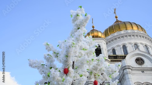 View of Cathedral of Christ the Saviour and branches with white blooming flowers and red Easter eggs in Moscow, Russia. Clear blue sky. Real time video. Easter holiday theme.