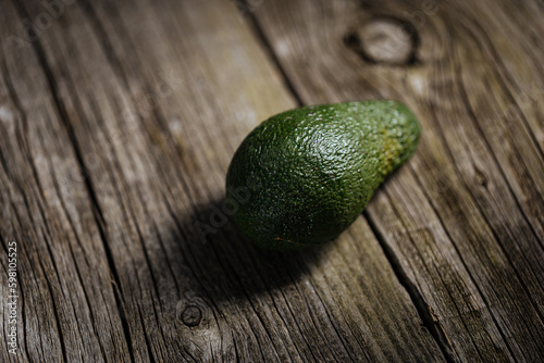 One Avocado Fruit on Rustic Wooden Table and Dramatic Mood. Stock Photo