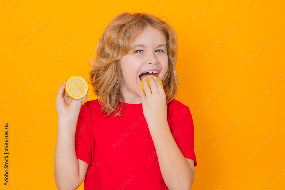 Kids face with fruits. Child eat lemon in studio. Studio portrait of cute kid boy lick lemon isolated on yellow. Kids face with fruits. Child eat lemon in studio. Studio portrait of cute kid boy lick lemon isolated on yellow.