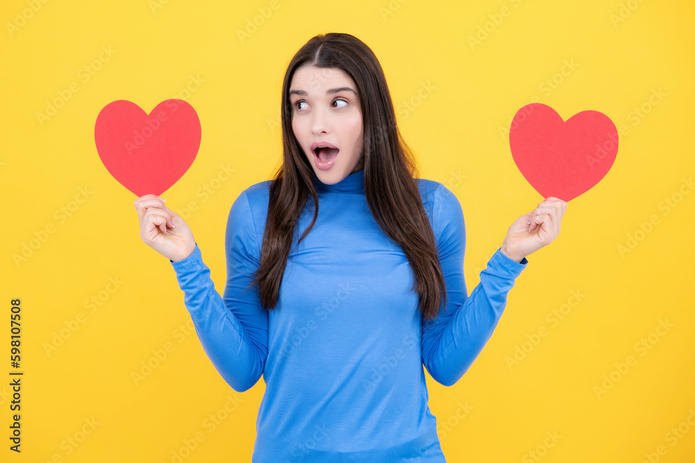 Portrait of lovely sweet cute pretty girl hold red paper card heart isolated over yellow background. Beautiful girl holding heart, love shape. Portrait of lovely sweet cute pretty girl hold red paper card heart isolated over yellow background. Beautiful girl holding heart, love shape.
