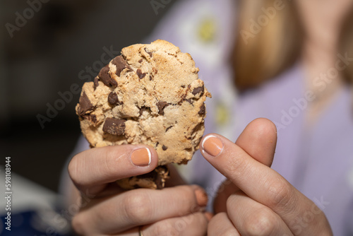 cookie au chocolat dans les mains d'une jeune fille faisant un coeur avec ses doigts photo