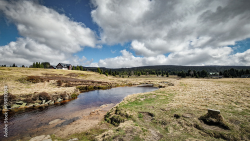 Rural grassland landscape in the settlement of Jizerka in the Jizera Mountains. Stream in the Jizerka Hamlet in the spring season. 