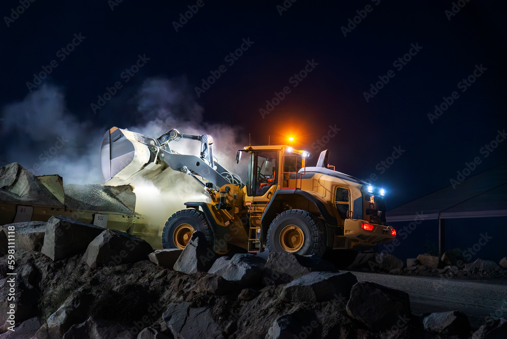 Heavy construction and mining machinery unloading gravel into silos on the night shift. Heavy construction and mining machinery unloading gravel into silos on the night shift.