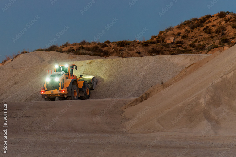 Heavy construction and mining machinery filling the bucket of a stockpile in the morning. Heavy construction and mining machinery filling the bucket of a stockpile in the morning.