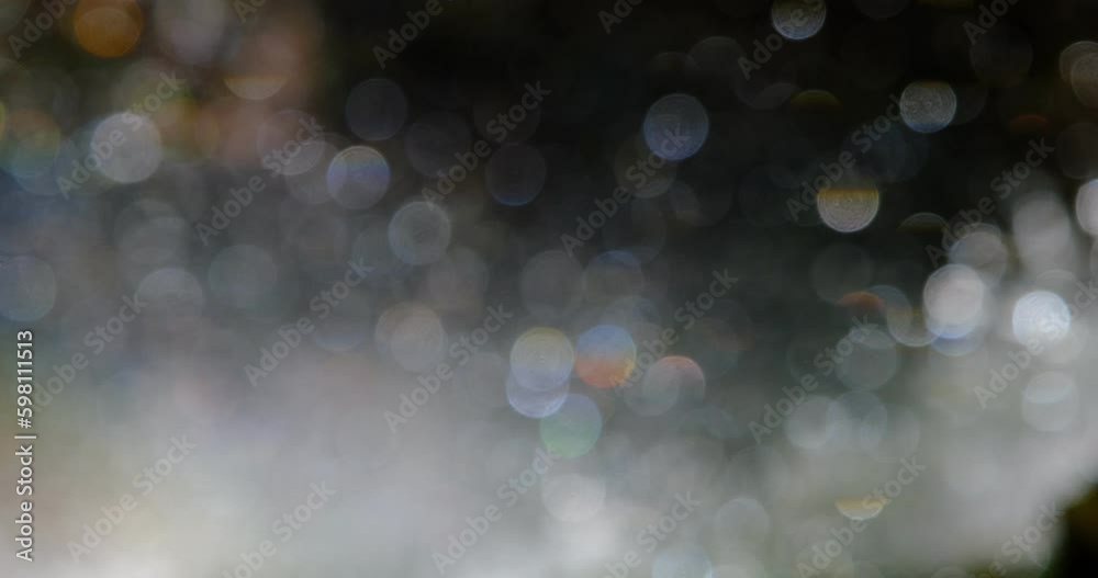 defocused slow motion view of cascade stream with rainbow reflection of light, bokeh light circles