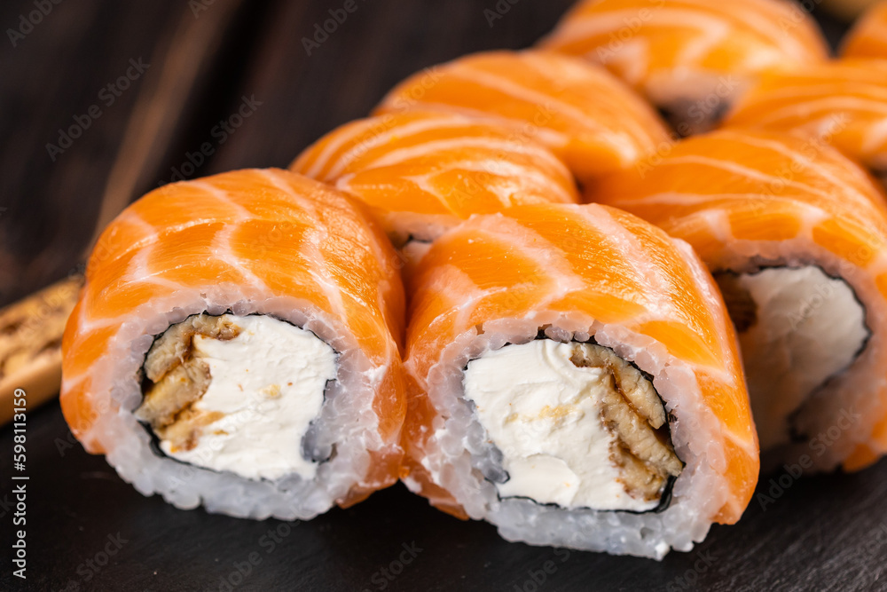 Close up Sushi roll philadelphia with salmon and eel and cream cheese on black background close-up. Sushi menu. Japanese food concept Close up Sushi roll philadelphia with salmon and eel and cream cheese on black background close-up. Sushi menu. Japanese food concept