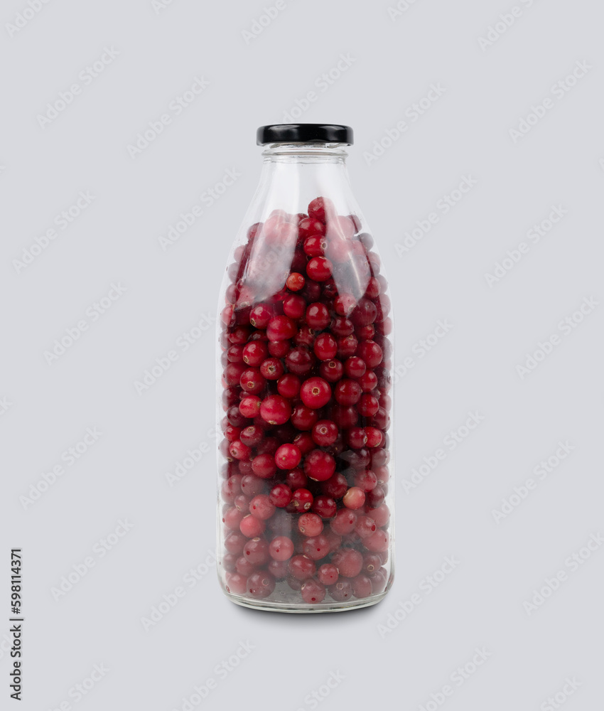 Bottle with wild cranberries and lingonberries on a gray isolated background. Healthy drink concept. Bottle with wild cranberries and lingonberries on a gray isolated background. Healthy drink concept.